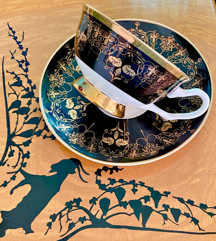 Stylish Black and Gold Something Wicked Nouveau Teacup and Saucer displayed on an artistic wooden background, highlighting the luxurious design and gold accents.