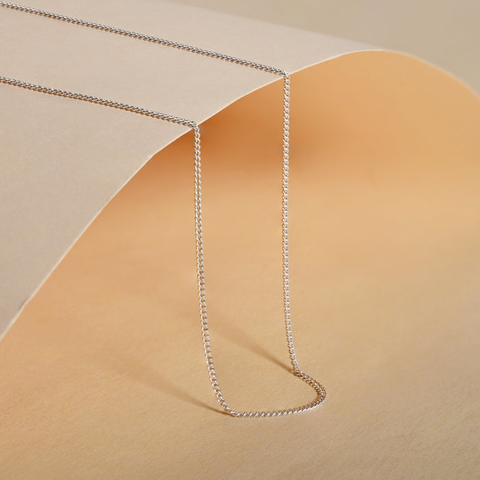 Silver chain necklace on a beige background
